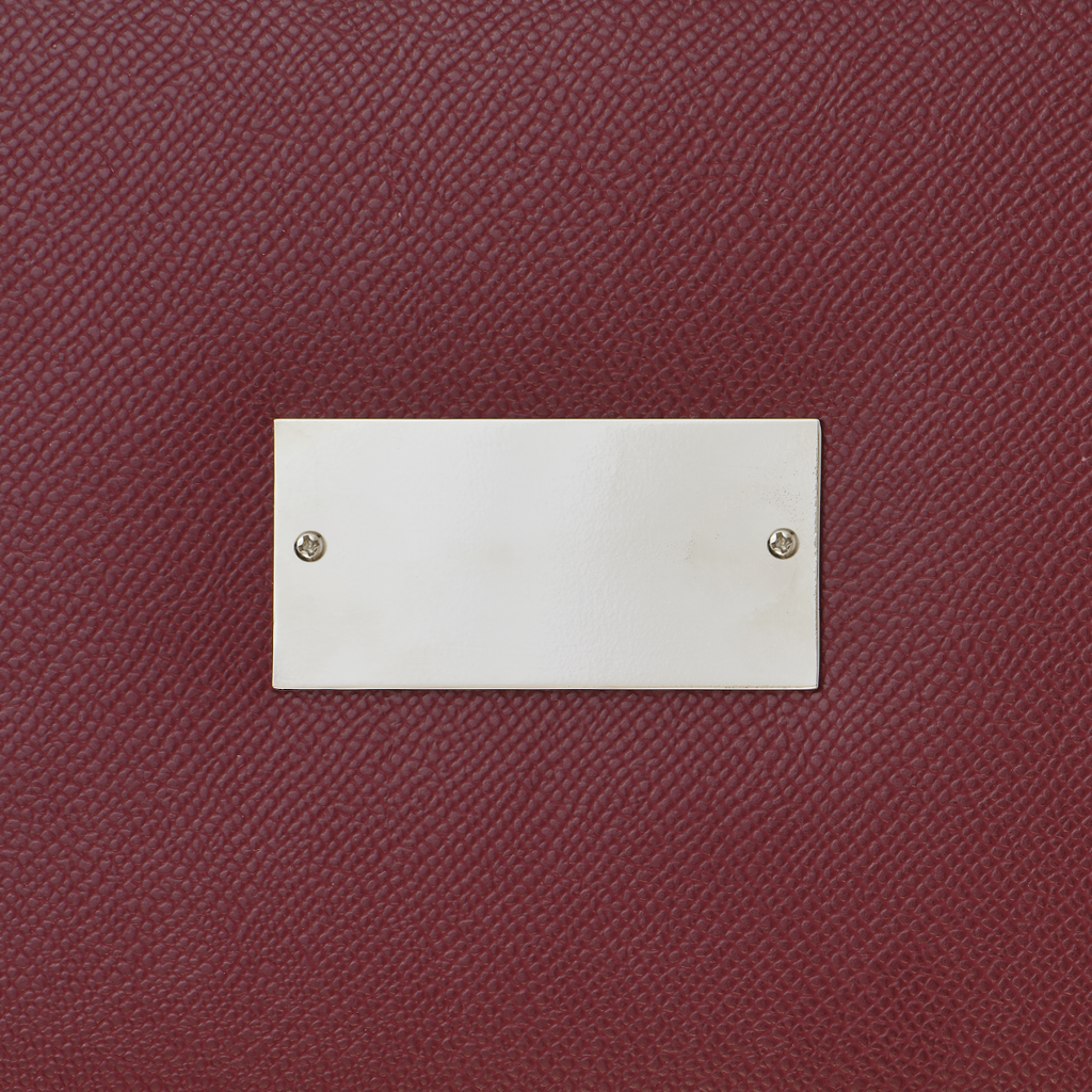 Close-up of a burgundy textured surface with a silver rectangular plaque.