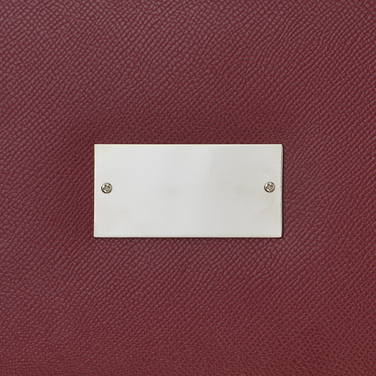 Close-up of a burgundy textured surface with a silver rectangular plaque.